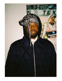 a man in a jacket and hat standing in front of a picture
